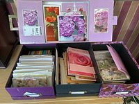Image showing two open stationery boxes containing a variety of greeting cards and envelopes with floral designs.