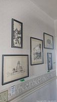Photo showing five of the seven framed sketch prints hanging on a wall, featuring architectural scenes from Toronto and Quebec in black and white.