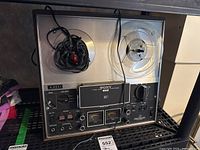 Full front view of the Sony three head stereo tape recorder with one reel on the take-up side, cables placed on left reel, power switch on right, and VU meters center.