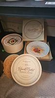 Image showing two round plate boxes labeled 'Williams-Sonoma Harvest Market Dessert Plates'. One box open with a scalloped tart plate inside.