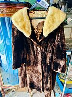 Full view of the dark brown beaver fur coat featuring a soft, light-colored collar and floral satin lining.