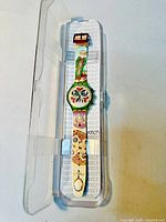 Full view of the Swatch chronograph watch in its original clear plastic box, displaying the colorful strap and dial with Russian-themed artwork.