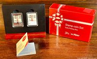 Front view of silver proof coins in black display stand alongside original red presentation box.