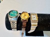 Photo of all three Seiko watches displayed on a black cushion, showing their faces and bands.