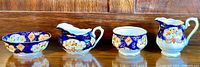 Full view of all four items - two sugar bowls and two creamers with detailed floral and cobalt blue designs