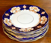 Stack of eight Royal Albert Derby Heirloom patterned salad/side plates showing the ornate blue and gold floral design with scalloped edges.