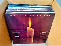 Box full of 1980s vinyl albums seen from top showing album spines and front of 'Conspiracy of Hope' album.