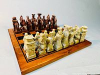 Chess pieces set up on wooden chess board. Pieces carved with Chinese characters and pagodas in brown and ivory colors.