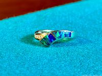 Close-up photo showing the curved sterling silver band with rectangular inlaid blue-green opal stones.