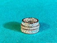 Photo showing the three sterling silver CZ eternity rings stacked on top of each other on a teal fabric background.