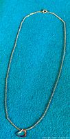 Full view of the 9ct gold necklace laid flat, showing chain and heart pendant.