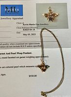 Appraisal certificate from Facets Gem Services Inc dated May 5, 2025, with pendant and chain laid atop