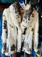 Front view of rabbit fur coat on hanger showing cream and brown spotted pattern and notch collar.