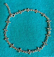 Full view of the sterling silver modernist bracelet laid flat showing linked cross-like elements and extension chain.