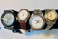 Four vintage Swiss Army wrist watches displayed on black stand, showing various designs and bands.