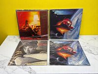 Four vinyl records arranged with two on top and two below against a yellow background, showing front album covers.