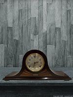 Front angled view of the vintage Sessions mantel clock showing the curved wood case with decorative inlay, brass bezel, and aged dial with spade-style hands.