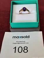 Front view of vintage gold ring with oval amethyst sitting in ring box