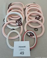 Overall view of 12 round and 2 oval crafting frames with tags, arranged in two stacks with a MaxSold lot tag visible.