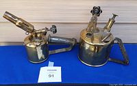 Two antique brass blow torches, one large with handle and valve, one medium marked 'PRIMUS No 82'