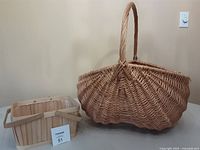Side view of the two baskets placed side by side, showing the large oval basket with a handle and the smaller rectangular basket.