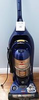 Front view of Bissell PowerForce Helix vacuum showing blue and gold design, clear dust container, control dial, and attached mini vacuum on the handle.