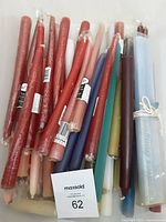 Photo showing approximately 30 assorted taper candles in various colors and lengths, mostly new and bagged, a few loose, laid side by side.