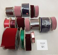 Photo showing 17 ribbon spools in various colors and materials including velvet, satin, and shiny. Ribbons vary from 1 to 3 inches wide and are in different states of fullness.