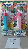 Front view of two flamingo PEZ dispensers in blue and pink, both in original packaging with tropical flamingo background and limited edition sticker.
