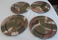 Top view showing the 4 hand thrown pottery servers or chargers with multi shades of brown and green glaze.