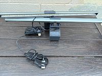 Two Lofter LED light bars with black adjustable mounts and USB cables, placed on a wooden surface.