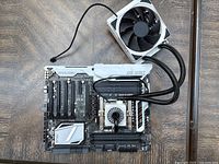 Top angled view of Asus X99 Series motherboard showing Crystal Sound 2 audio circuit area, multiple PCIe slots, DDR4 DIMM slots, and attached liquid cooling block with hoses connected to radiator fan.