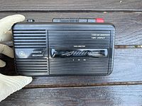 Front view of a GE black cassette recorder showing speaker grille, tape direction slider, and control labels.