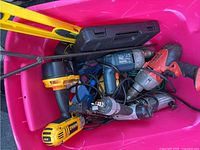 Top view of the container showing multiple power tools including Dewalt cordless drill, pneumatic nailers, electric drill, and hand tools with yellow level and black case.