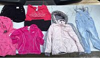 Photo of six girls kids clothing items laid out including jackets, hoodies, shorts, and overalls