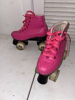 Photo showing pair of pink kids roller skates, front and side angle, highlighting the size 38 and condition