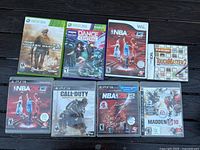 Photo showing eight video game cases for Xbox 360, PS3, Wii, and Nintendo DS with visible scratches