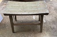 Side and front angled view of the small wooden outdoor bench with visible wear and weathered surface.