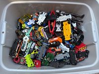 Top view showing the large quantity of Hot Wheels toy cars in various colors and styles inside the plastic storage bin.