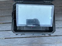 Top view of the touch screen stereo unit with visible icons on left side of the screen and Power Acostic branding below the display inside a protective case.