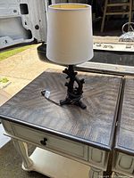 Full view of the rustic tree branch lamp with white shade on a wooden table outdoors.