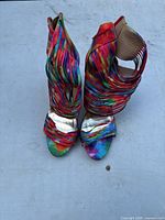 Front view of the pair of women's rainbow open toe high heel sandals showing multiple thin multicolor straps and metallic silver interior sole.