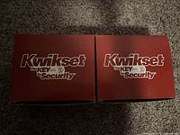 Two sealed red Kwikset boxes with branding 'Kwikset The Key to Security' showing original packaging condition.