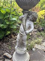 Angled close-up of the cherub figure from the side with clear view of facial expression and detailed top of the twisted column supporting the basin.