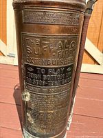 Close-up of embossed labeling 'The Buffalo Fire Extinguisher' with vintage operating instructions.