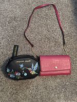 Christian Siriano black handbag with floral embroidery and Crown and Ivy pink purse shown side by side on carpeted floor