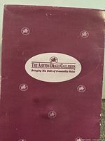 Image of the maroon-colored original box with 'The Ashton-Drake Galleries' branding on top, showing some wear and damage.