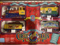 Full view of the Echo Circus Musical Train Set in original packaging, showing locomotive and four train cars inside a red box with circus graphics.