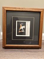 Medium-sized framed print artwork of a child holding a white cat, captured with visible black and cream double matting and wood frame