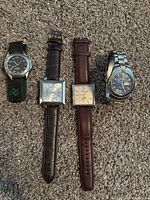 Four men’s vintage analog watches including a Fossil chronograph with square case and leather strap and three other watches with leather and metal bands